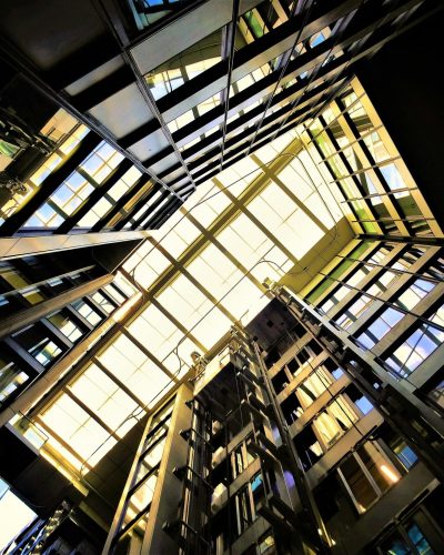 Dynamic low-angle view of a modern building's glass ceiling showcasing reflections and light.